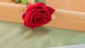 Ein Tablett mit einem Croissant, einer Teetasse und einer roten Rose.