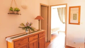A hallway with a wooden cabinet, a hanging plant, a lamp, and a framed picture on the wall. - Cosy gîte for 6 people in the heart of the Fontfroide massif (Narbonne)