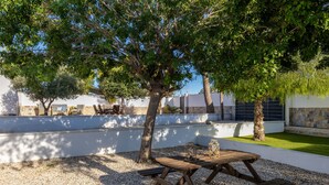An outdoor patio with a wooden table and benches, surrounded by gravel and trees. - Psicomagia Deluxe Villa by Fidalsa (Dolores)
