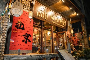 A hotel entrance with a large sign in Chinese characters, a wooden facade, and traditional decor elements. - IMMERSING (Beijing)