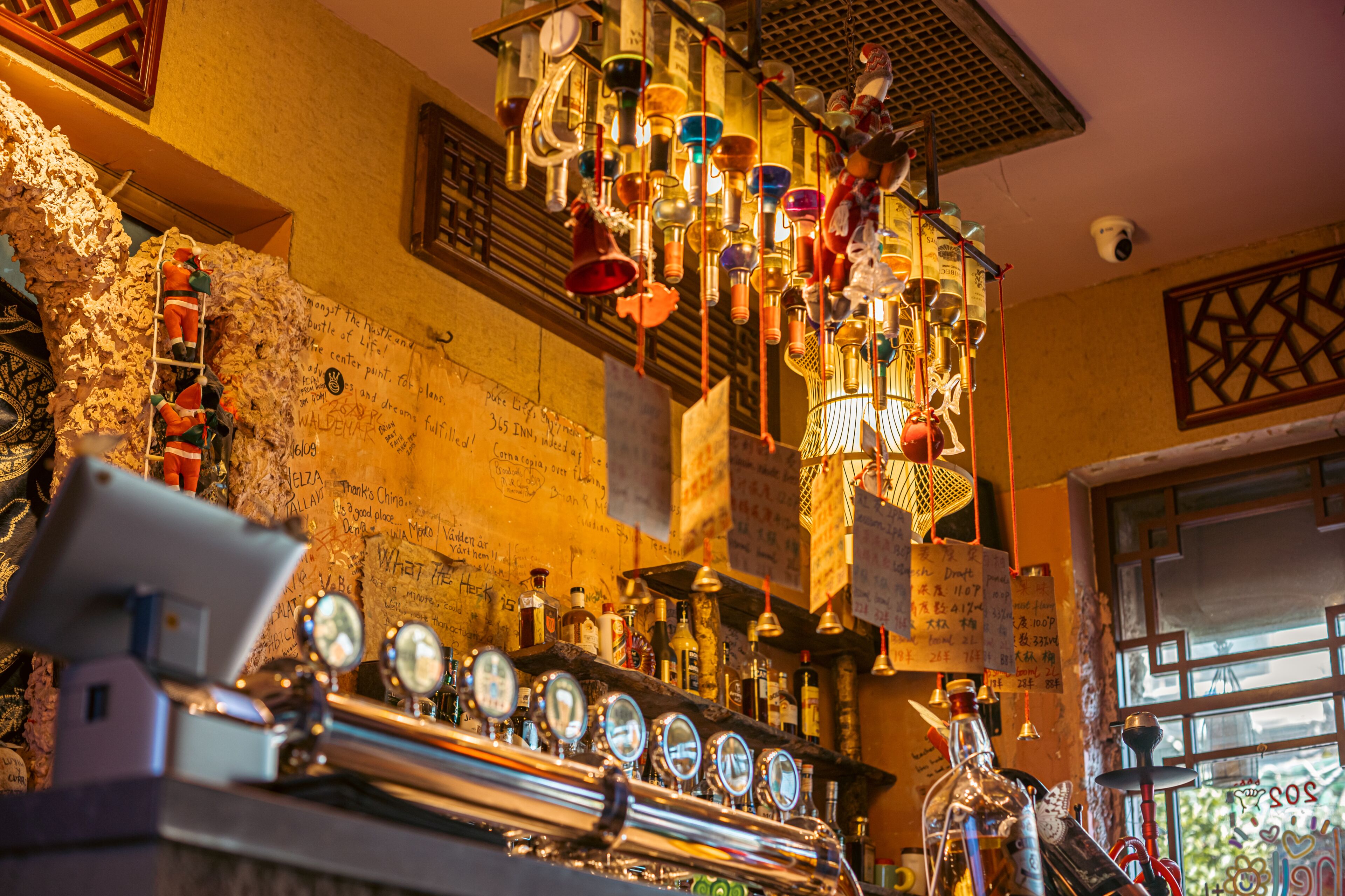 A bar with a beer tap, various bottles, and a decorative ceiling.