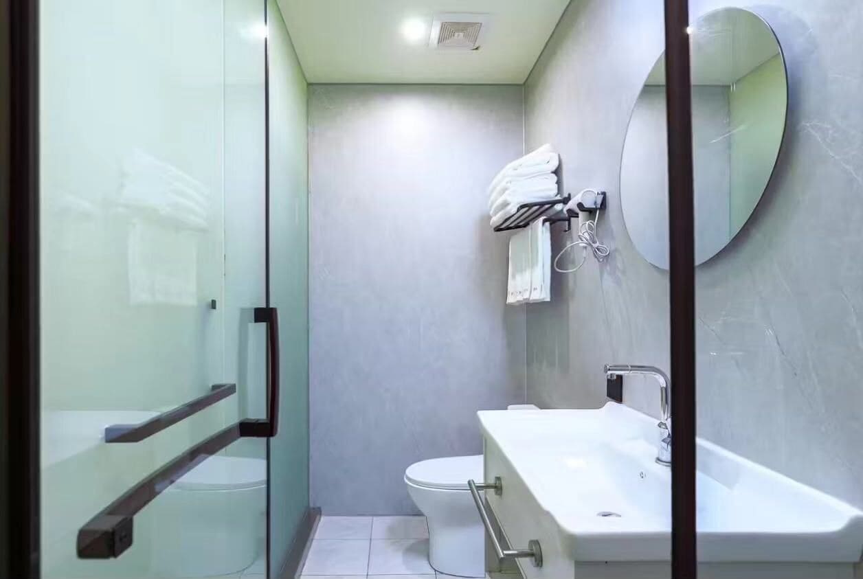 A modern bathroom with a glass shower enclosure, a toilet, and a sink with a mirror.