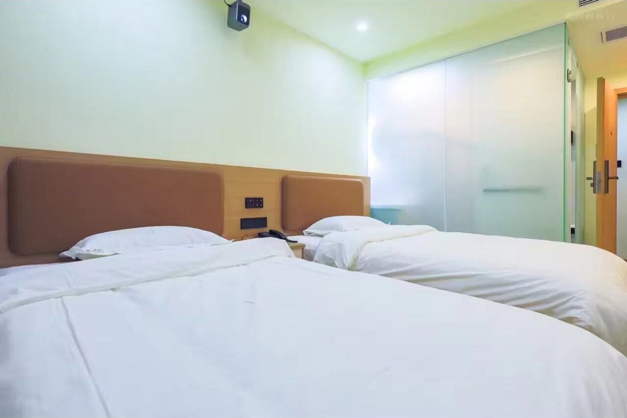 Une chambre d’hôtel avec deux lits, une tête de lit en bois, une table de chevet avec un téléphone et un miroir.