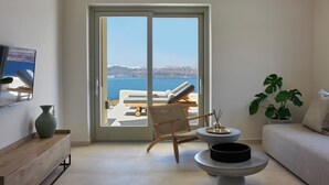 Een moderne woonkamer met een grote schuifpui die uitkomt op een balkon met uitzicht op zee.