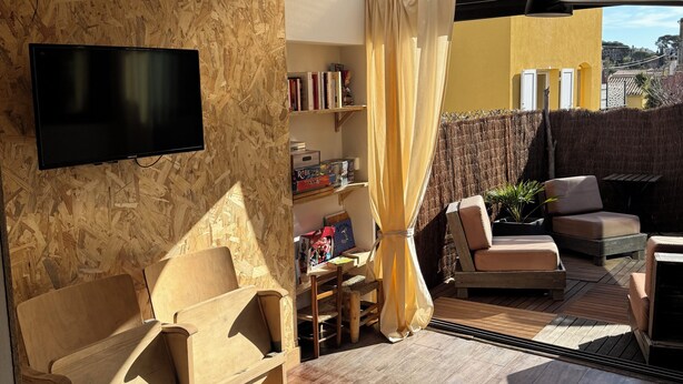 Una stanza luminosa con televisione a schermo piatto, mobili in legno, una libreria e vista sull'esterno.