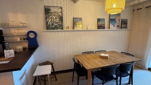 Zona pranzo con tavolo e sedie in legno, angolo bar con orologio e quadri appesi al muro.