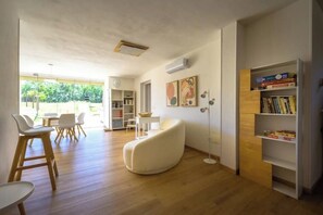 Ein modernes Wohnzimmer mit einer gebogenen Couch, einem Bücherregal und einem Essbereich mit Stühlen und einem Tisch.