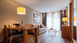 A modern hotel room with a dining area, a sofa, and a small table.
