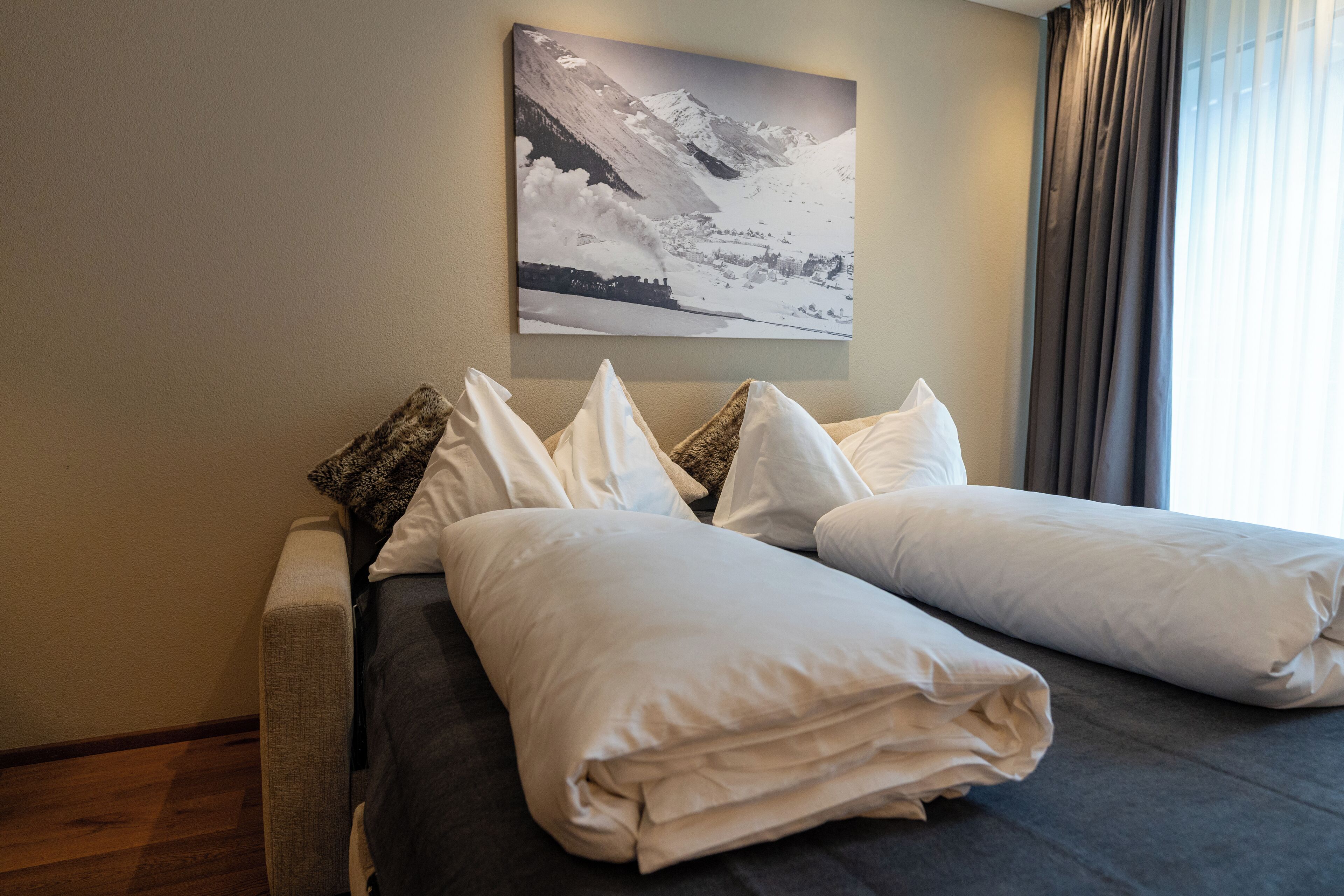 Une chambre d’hôtel avec un lit, des oreillers et un tableau représentant un paysage de montagne accroché au mur.
