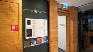 A hotel entrance with a wooden interior, a sign for 'Apart's Crown', and a directory board with room information.