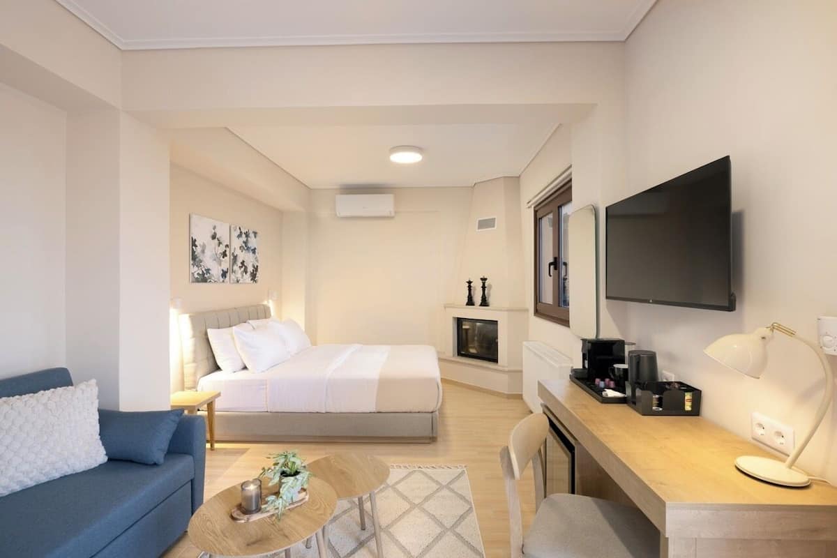 Een moderne hotelkamer met een bed, een bureau met een flatscreen televisie, een bank en een salontafel.