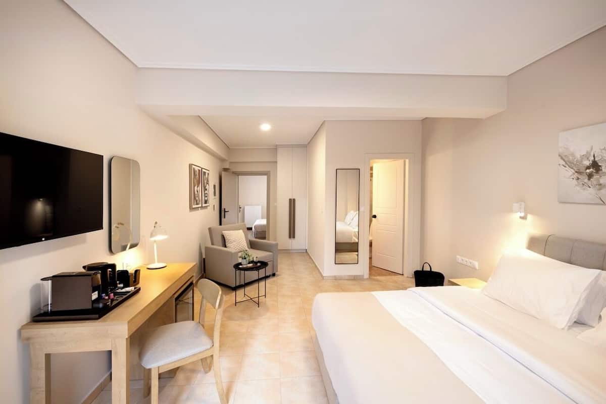 Een hotelkamer met een bed, een bureau met stoel, een televisie en een spiegel.