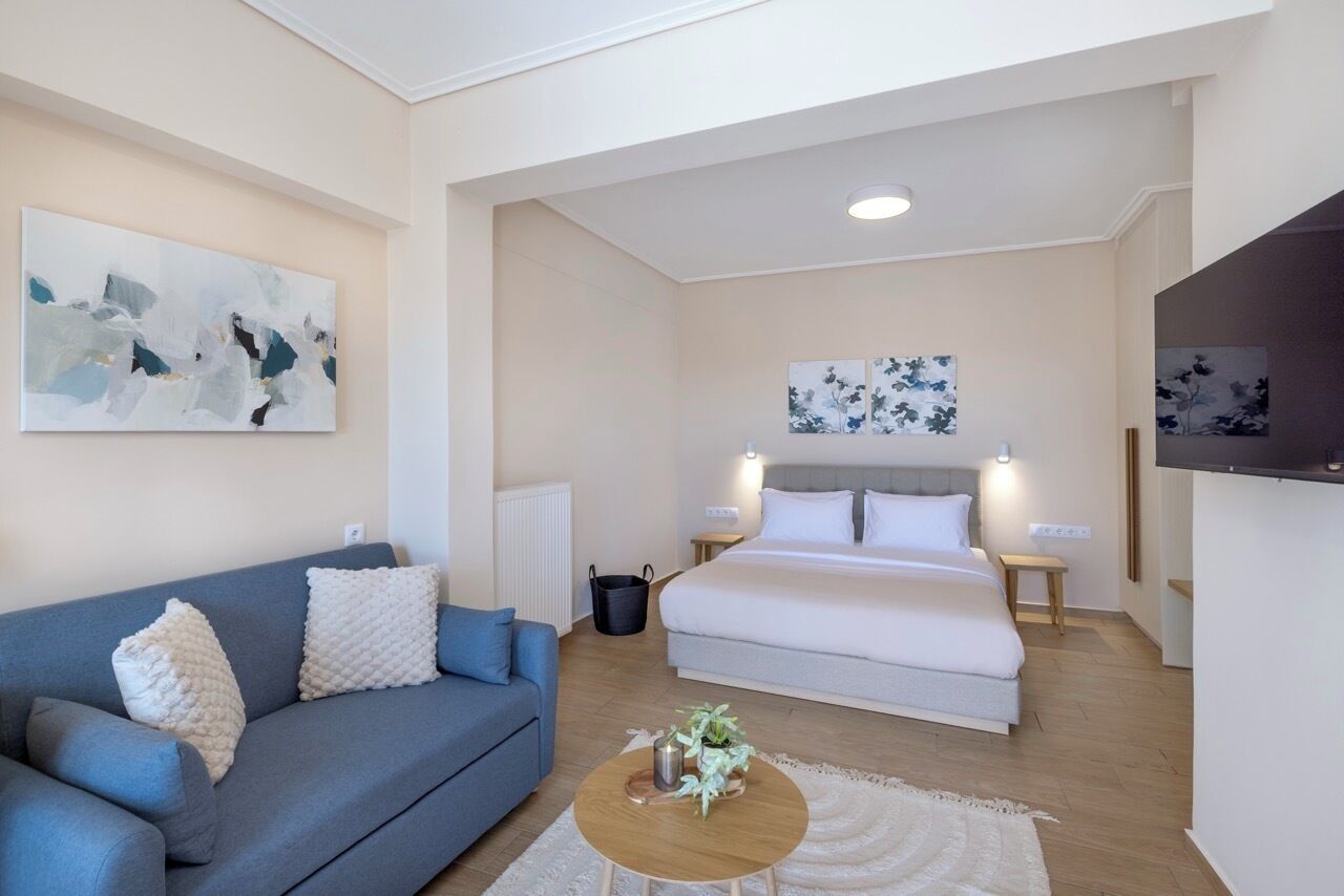 Ein modernes Hotelzimmer mit einem großen Bett, einer Couch, einem Couchtisch und Bildern an den Wänden.