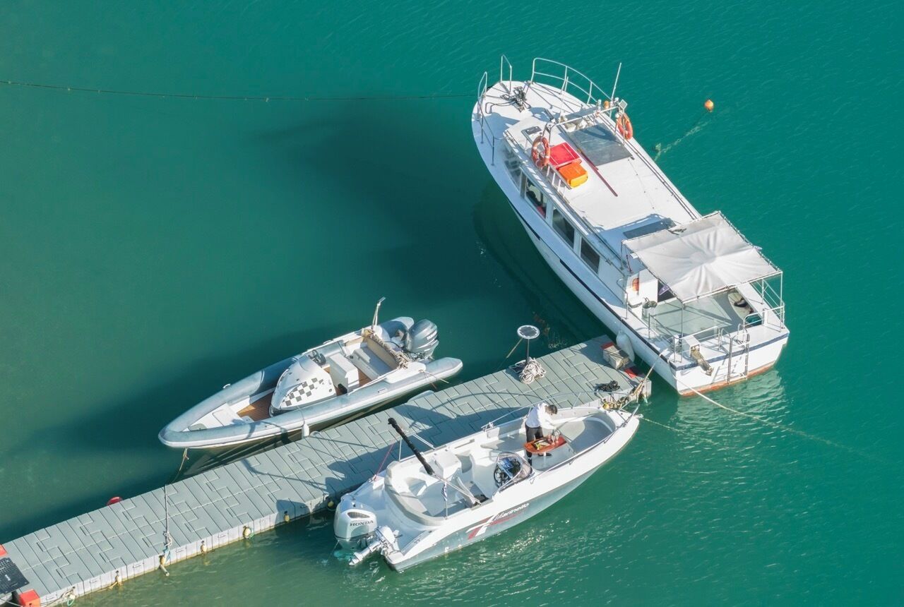 A large boat docked at a pier with two smaller boats moored alongside.