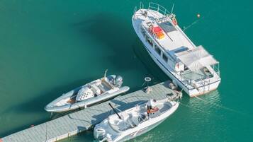 A large boat docked at a pier with two smaller boats moored alongside.
