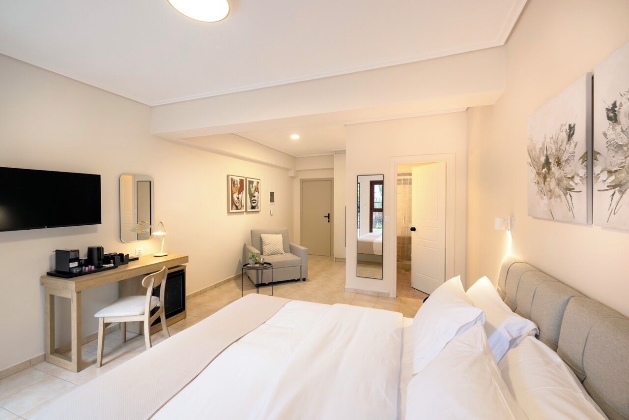 Una habitación de hotel moderna con una cama grande, un escritorio con silla, televisión y obras de arte en las paredes.