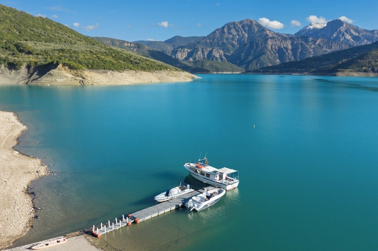 Un bote amarrado en un muelle, con montañas al fondo.