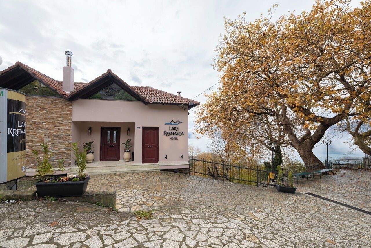 Ein Hotel mit steinverkleideter Fassade, einem roten Ziegeldach und einem Schild mit der Aufschrift 'Lake Kremasta Hotel'.