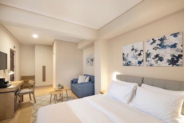 A hotel room with a bed, a desk, a chair, a sofa, and artwork on the walls. - Lake Kremasta Hotel (Agrafa)