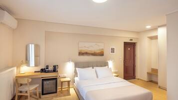 Une chambre d’hôtel équipée d’un lit, d’un bureau avec un ordinateur, d’une chaise, d’un petit réfrigérateur et d’une porte signalée comme issue de secours.