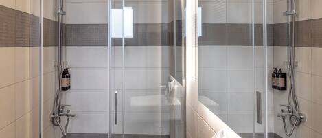 A modern bathroom with a glass-enclosed shower, a white sink, and a large mirror.