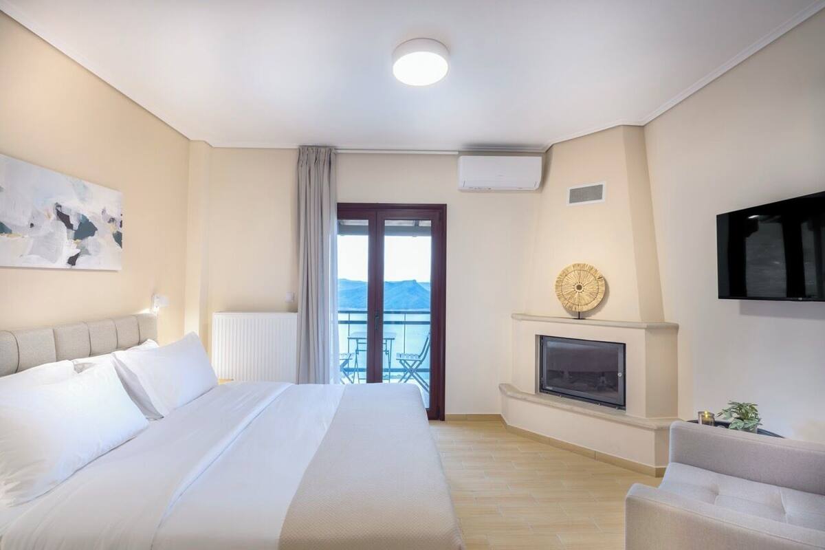 Een hotelkamer met een bed, een televisie, een open haard en een balkon met uitzicht.