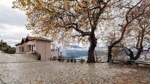 A stone-paved area with a building and a tree. - Lake Kremasta Hotel (Agrafa)