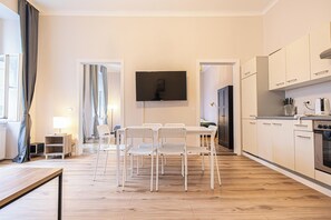 A modern kitchen with white cabinets, a built-in oven, and a flat-screen TV mounted above the counter. - Stylish 2BR Apartment Vienna Center (Vienna)