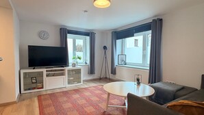 A modern living room with a flat-screen TV, a white coffee table, a sofa, and a patterned rug. - Apartment "Fewo Im Schönen Allensbach" with Lake View and Wi-Fi (Allensbach)