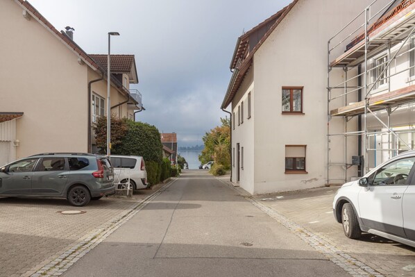 A residential street with parked cars, houses, and a clear view of a lake in the distance. - Apartment "Fewo Im Schönen Allensbach" with Lake View and Wi-Fi (Allensbach)