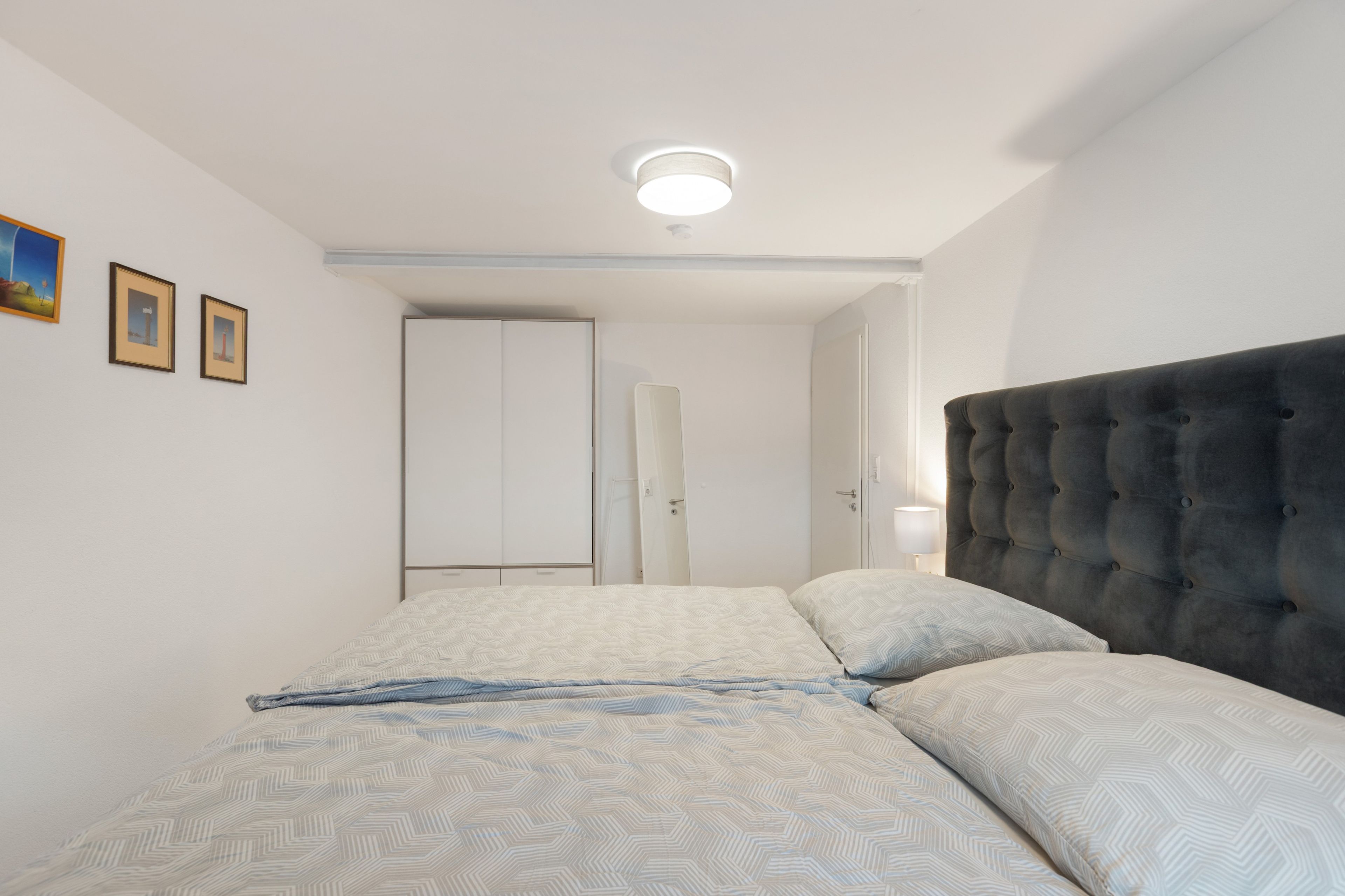 A bedroom with a bed, a headboard, and a ceiling light.