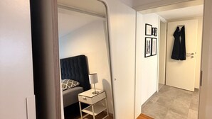 A room with a bed, a nightstand, a mirror, and a door leading to another room. - Apartment "Fewo Im Schönen Allensbach" with Lake View and Wi-Fi (Allensbach)