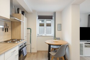 Una cocina compacta con estufa, horno y comedor con mesa y sillas.