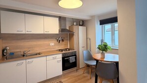 A modern kitchen with white cabinets, a wooden countertop, a built-in oven, and a dining area with a table and chairs. - Apartment "Fewo Im Schönen Allensbach" with Lake View and Wi-Fi (Allensbach)