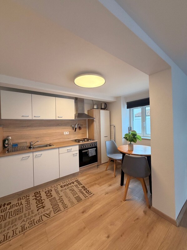 Eine moderne Küche mit weißen Schränken, einer Holz Arbeitsplatte, einem eingebauten Backofen und einem Essbereich mit Tisch und Stühlen.