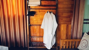 A wooden room with a bench, a rack with towels, and a bed. - Havenora Retreat (Tay Hoa Lu)
