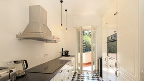 A kitchen with a black countertop, stainless steel appliances, a white range hood, and a checkered floor. - Lake 270 Apartment (stresa)