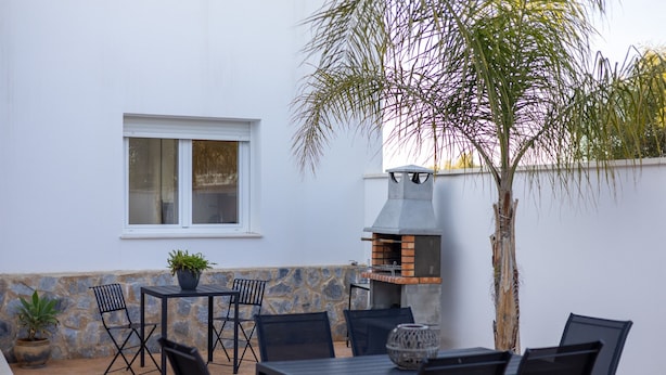 An outdoor patio with a stone wall, a grill, and a potted plant. - Psicomagia Deluxe Villa by Fidalsa (Dolores)