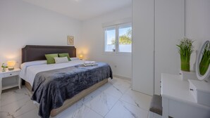 A modern bedroom with a bed, bedside tables, a nightstand, a dresser, a mirror, and a window. - Psicomagia Deluxe Villa by Fidalsa (Dolores)