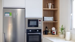 A modern kitchen with a stainless steel refrigerator, a built-in microwave, and a double oven. There is a wooden shelf with jars and a coffee machine. - Psicomagia Deluxe Villa by Fidalsa (Dolores)