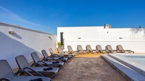 A poolside area with lounge chairs arranged in rows, a concrete pathway leading to the pool, and a white building in the background. - Psicomagia Deluxe Villa by Fidalsa (Dolores)