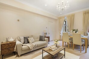 A living room with a sofa, coffee table, and dining area with chairs and a table. - Upscale Central London Apartment (London)