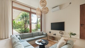A modern living room with a sectional sofa, a coffee table, and a flat-screen TV. - Manu Villas (Denpasar)