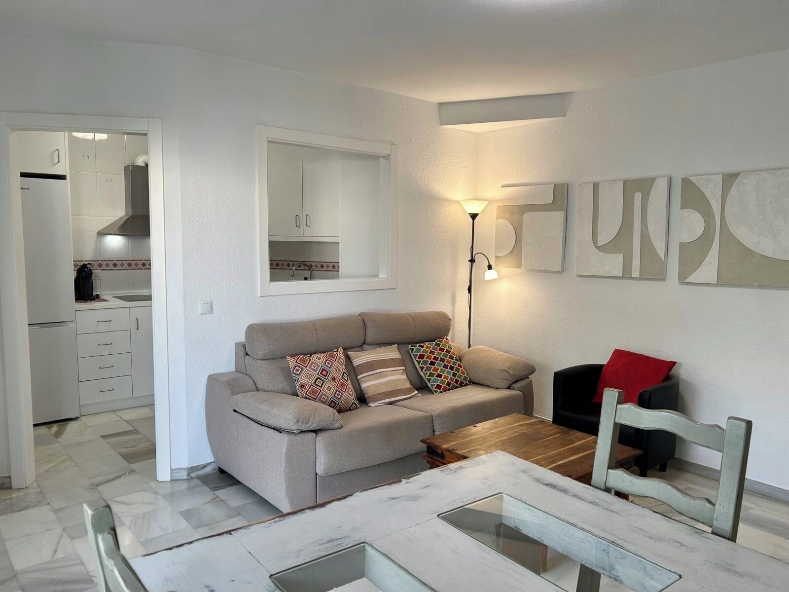 A modern living room with a sofa, coffee table, and a dining area with a glass-top table.