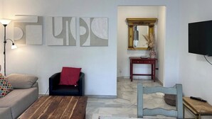 A living room with a sofa, a coffee table, a TV, and abstract wall art. - CasaMar Playa (Estepona)
