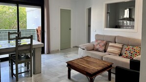 A modern living room with a sofa, a coffee table, and a dining area with chairs. - CasaMar Playa (Estepona)