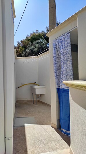 A small, enclosed bathroom with a white sink, a blue shower curtain, and a tiled floor. - La Casetta Di Novaglie - Puntaverde Con Vista Mare (Alessano)