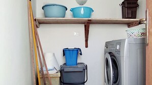 A laundry room with a washing machine, a blue bucket, and a broom. - La Casetta Di Novaglie - Puntaverde Con Vista Mare (Alessano)