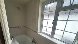 Ein Badezimmer mit Badewanne, Dusche und Fenster.