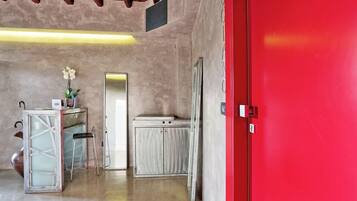 A room with a red door, a white cabinet, a stool, and a mirror.